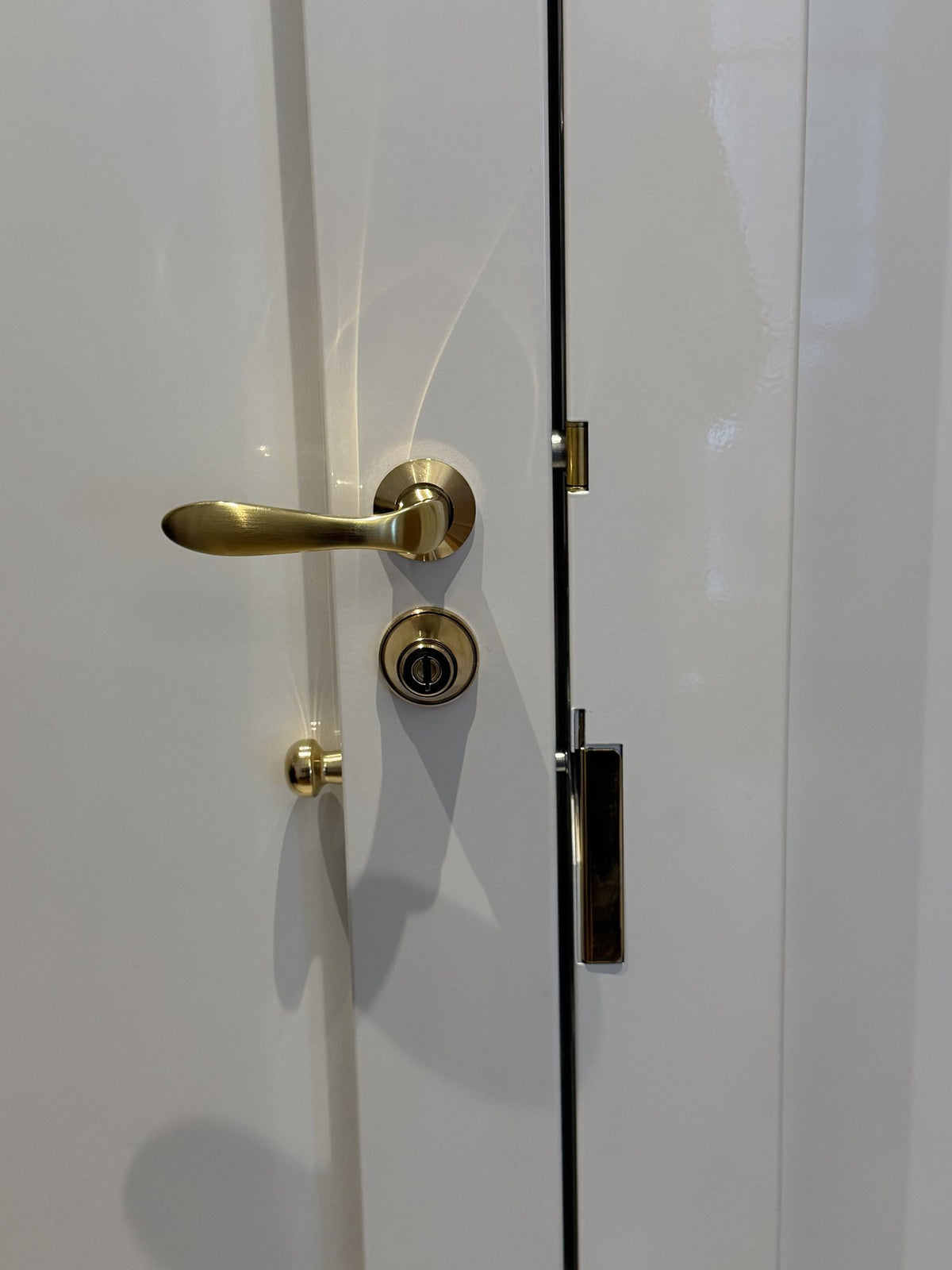 Béquille, cylindre et bouton en laiton posés sur une porte d’appartement à Paris